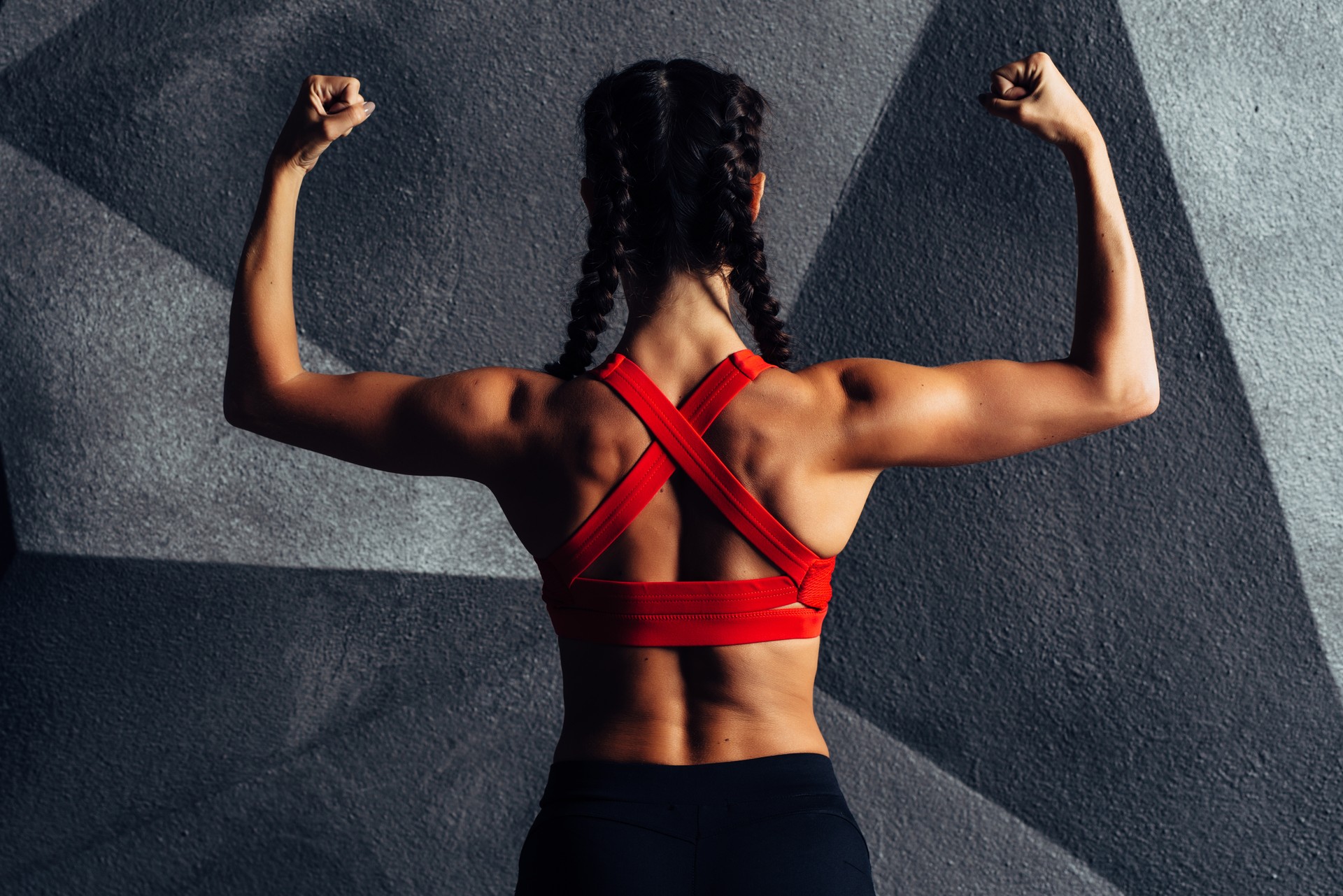 Back view portrait of a fitness woman showing biceps